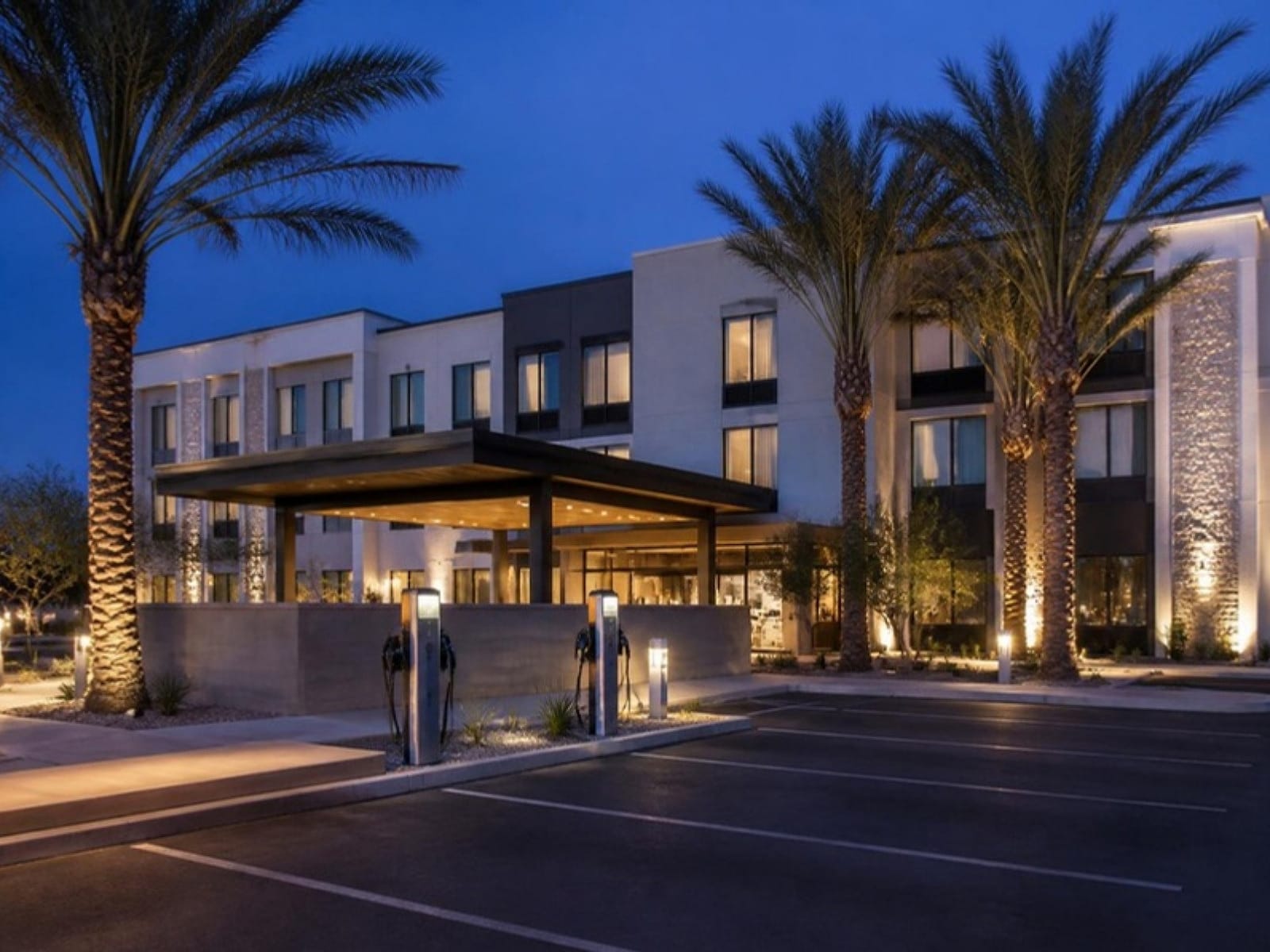 Modern boutique hotel exterior at twilight with EV charging stations